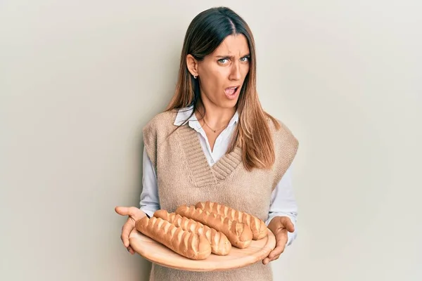 Брюнетка Молодая Женщина Держит Домашний Хлеб Шоковом Лице Смотрит Скептически — стоковое фото