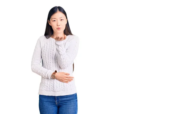 カジュアルなセーターを着た若い美しい中国人女性がカメラを見て 愛とセクシーさを手でキスを吹いています 愛の表現 — ストック写真
