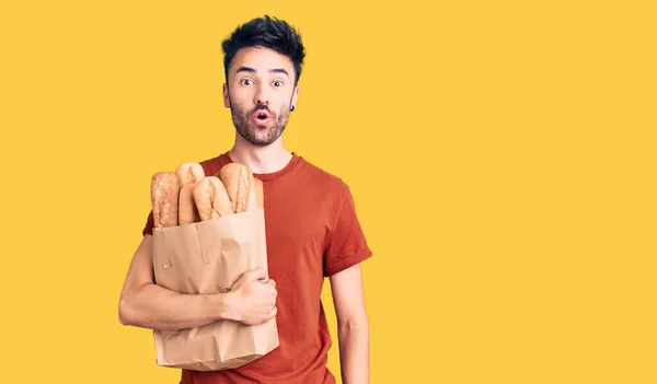 Young Hispanic Man Holding Paper Bag Bread Scared Amazed Open — Stock Photo, Image