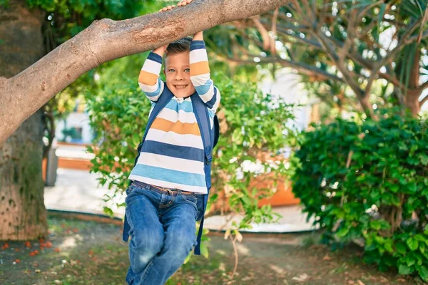可爱的高加索学生男孩笑着高高兴兴地挂在公园的树枝上 — 图库照片