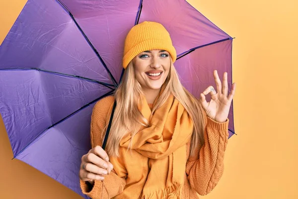 若いです白人女性を保持紫色の傘を持っています指でOkサインを行います 笑顔優しいジェスチャー優れたシンボル — ストック写真