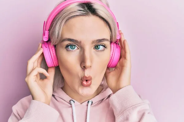 Chica Rubia Joven Escuchando Música Usando Auriculares Haciendo Cara Pez — Foto de Stock