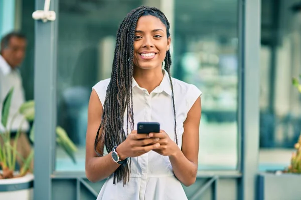 若いアフリカ系アメリカ人の女性が市内のスマートフォンを使って笑顔で — ストック写真
