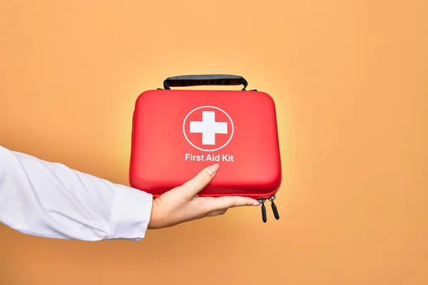 Hand of caucasian young woman holding first aid kit briefcase over isolated white background