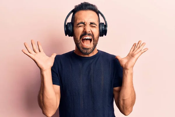 Young Hispanic Man Listening Music Using Headphones Celebrating Mad Crazy — Stock Photo, Image