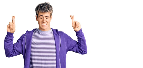 Young Handsome Man Wearing Casual Purple Sweatshirt Gesturing Finger Crossed — Stock Photo, Image
