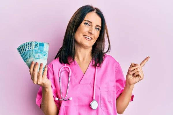 Middle Age Brunette Doctor Woman Holding 100 Brazilian Reals Banknotes — 图库照片