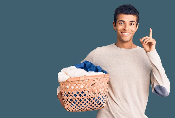 Young African Amercian Man Holding Laundry Basket Surprised Idea Question — Stockfoto