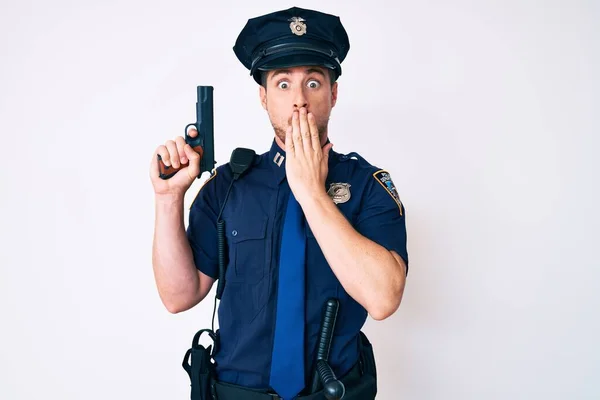 警察の制服を着た若い白人男性が口を手で覆い ショックを受け 間違いを恐れて銃を持っていた 驚きの表情 — ストック写真