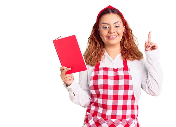 Jovem Latina Vestindo Avental Segurando Livro Receitas Surpreso Com Uma — Fotografia de Stock