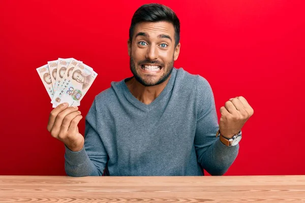 Hombre Hispano Guapo Sosteniendo Billetes Chinos Yuan Gritando Orgulloso Celebrando —  Fotos de Stock