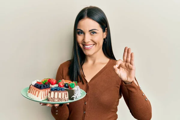 Junge Brünette Frau Hält Teller Mit Kuchenscheiben Und Tut Zeichen — Stockfoto