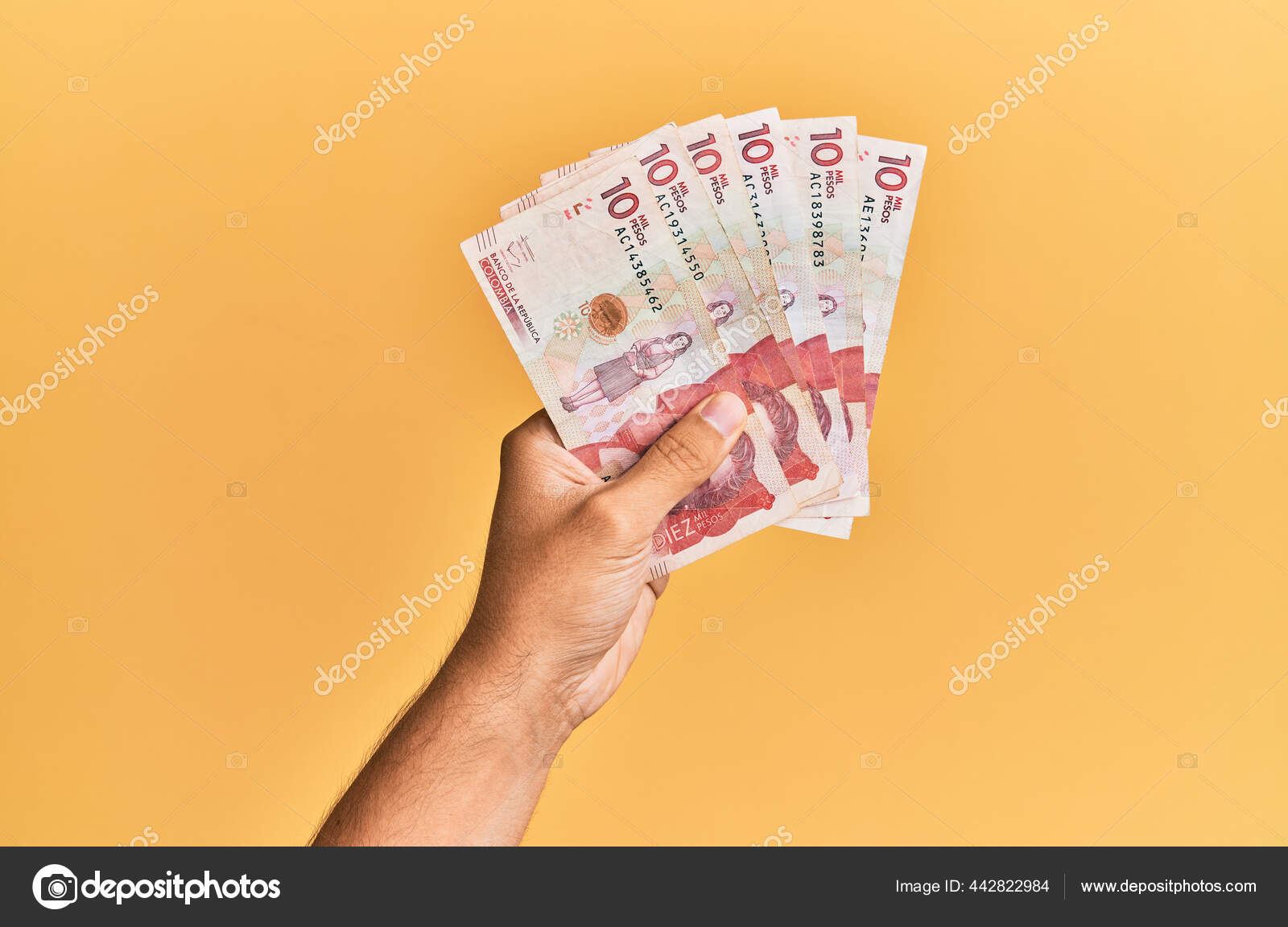 在孤立的黄色背景上拿着10比索钞票的惊慌失措的人的手——图库图片© Krakenimages.com #442822984