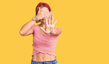 Gündelik kıyafetler giyen genç sarışın kadın ve ellerle gözlerini kapatan Diadem üzgün ve korku ifadeleriyle jest yapıyor. utangaç ve olumsuz kavram. 