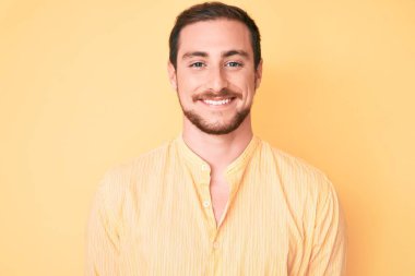 Yüzünde mutlu ve havalı bir gülümseme olan sıradan kıyafetler giyen genç yakışıklı bir adam. şanslı kişi. 