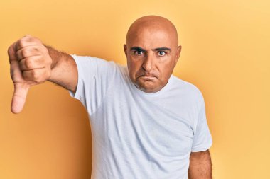 Olgun Orta Doğulu adam, sıradan beyaz tişört giyiyor mutsuz ve kızgın görünüyor, reddediliyor ve olumsuz bir hareket yapıyor. kötü ifade. 