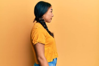 Gündelik giysiler giyen genç Latin kadın, yan tarafa bakıyor, rahat poz veriyor kendine güveni olan doğal bir yüz takınıyor.. 