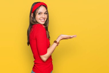 Genç esmer kadın, gündelik giysiler içinde avuçlarını açıp fotokopi alanını gösteren, gülümseyerek mutlu bir şekilde gülümseyen. 