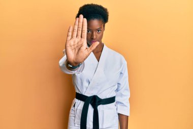 Karate kimonosu ve siyah kuşak giyen genç Afrikalı Amerikalı kız avucunun içi gibi şarkı söylemeyi kesiyor. Yüzünde olumsuz ve ciddi bir jest olan uyarı ifadesi. 