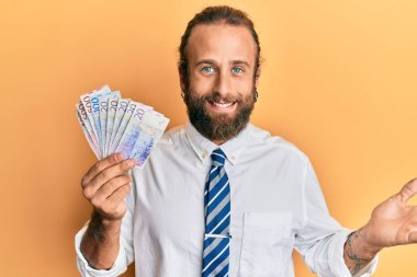 Sakallı, uzun saçlı, İsveçli banknotlar tutan yakışıklı adam başarıyı mutlu bir gülümsemeyle kutluyor ve kazanan el kaldırarak ifade ediyor. 