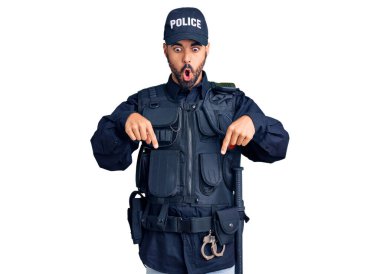 Polis üniforması giyen genç İspanyol adam parmaklarını göstererek reklamını yapıyor, şaşırmış yüz ve ağzını açıyor. 