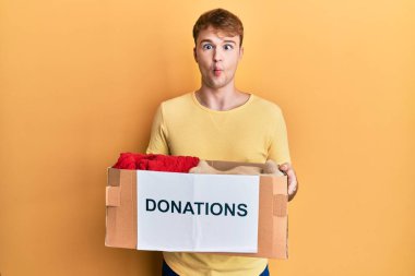 Hayır işi için bağış kutusu tutan genç beyaz bir adam. Ağzı ve şaşı gözleriyle balık suratı yapan çılgın ve komik bir adam.. 