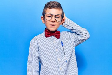 Cute blond kid wearing nerd bow tie and glasses confuse and wonder about question. uncertain with doubt, thinking with hand on head. pensive concept. 