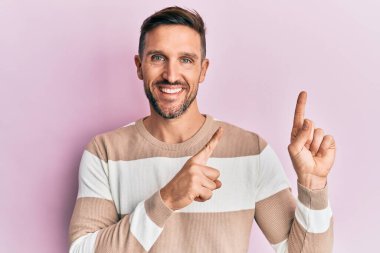 Sakallı, sıradan giyinmiş, gülümseyen ve kameraya bakan yakışıklı bir adam.. 