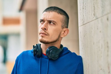 Şehirde kulaklık takan ciddi bir suratı olan genç bir İspanyol.