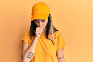 Teslimat üniforması giyen genç İspanyol kadın kendini kötü hissediyor ve soğuk algınlığı veya bronşitin belirtisi olarak öksürüyor. sağlık hizmeti kavramı. 