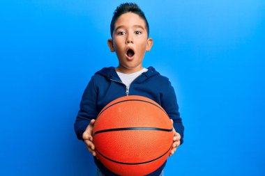 Küçük İspanyol çocuk elinde basketbol topu tutarken şaşkınlık ve şaşkınlık dolu bir ifade, korku ve heyecanlı bir yüz ifadesi vardı.. 