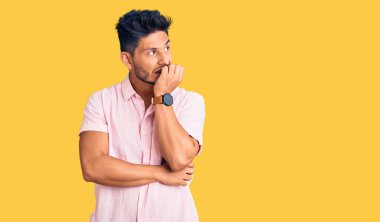 Gündelik tişört giyen yakışıklı Latin Amerikalı genç adam gergin ve gergin görünüyordu. Ağzı tırnak ısıran elleri vardı. anksiyete. 