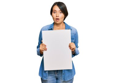 Kısa saçlı, boş afiş tutan güzel genç bir kadın. Şaşırtıcı bir şekilde ağzı açık, korkmuş ve hayrete düşmüş. İnanmayan bir yüz. 