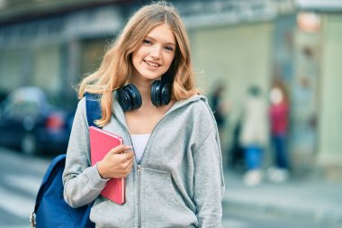 Güzel beyaz öğrenci şehirde kulaklık kullanıyor..