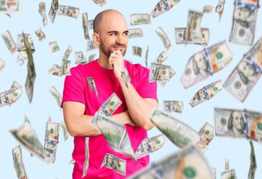 Elleri çenesinde gündelik tişört giyen genç ve yakışıklı bir adam soru sormayı düşünüyor, düşünceli bir ifade. Düşünceli bir yüzle gülümsüyor. şüphe kavramı.