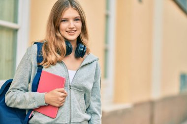 Güzel beyaz öğrenci şehirde kulaklık kullanıyor..