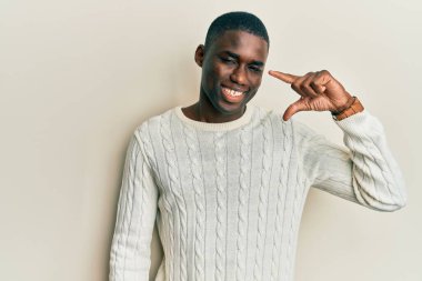 Gündelik kıyafetler giyen, gülümseyen, kendine güvenen, el hareketi yapan, parmaklarıyla işaret yapan ve kameraya bakan genç Afro-Amerikan bir adam. ölçüm kavramı. 