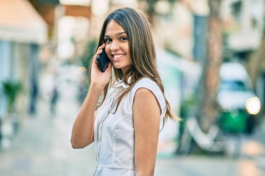 Güzel Latin genç kız gülümsüyor. Şehirde akıllı telefondan konuşan mutlu kız..
