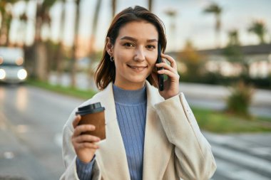 Genç İspanyol kadın akıllı telefondan konuşuyor ve şehirde kahve içiyor..