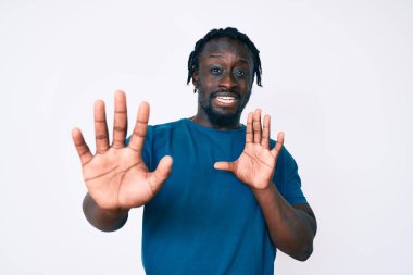 Saçları örgülü, korku ifadesinden korkan ve dehşete düşmüş genç Afro-Amerikan bir adam. El kol hareketi yapmayı kes, şok içinde bağır. panik konsepti. 