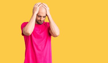 Genç yakışıklı bir adam günlük tişört giyiyor. Baş ağrısı, çaresiz ve stresli. Çünkü acı ve migren ağrısı var. Eller başının üstünde.. 