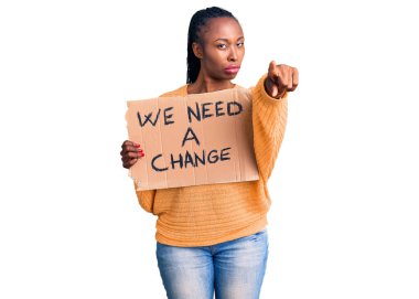 Elinde tutmakta olan Afrikalı genç bir Amerikalı kadın kamerayı işaret eden bir değişim pankartına ihtiyacımız var ve sen kendine güvenen ciddi görünüyorsun. 