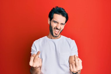 Young hispanic man wearing casual white tshirt showing middle finger doing fuck you bad expression, provocation and rude attitude. screaming excited 