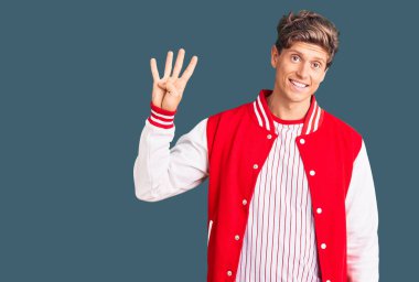 Beyzbol üniforması giyen yakışıklı genç adam dört numarayı gösterip işaret ederken kendinden emin ve mutlu bir şekilde gülümsüyor.. 