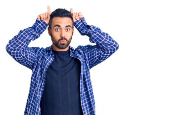 Gündelik kıyafetler giyen genç İspanyol adam boynuzlarını parmağında oynatarak komik hareketler yapıyor. 