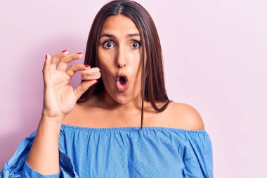 Genç, güzel, esmer bir kadın elinde makarna tutuyor. Korkmuş ve ağzı açık, şaşırmış ve şaşırmış. 