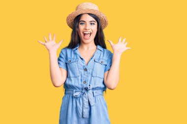 Yazlık şapkalı esmer kız çılgın ve başarıyı kollarını kaldırıp heyecanla haykırarak kutluyor. Kazanan konsept 