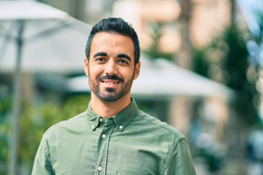 Genç İspanyol adam gülümseyerek şehirde mutlu mesut dikiliyor..