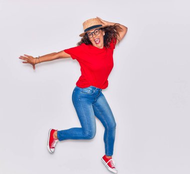 Orta yaşlı, güzel İspanyol bir kadın, sıradan kıyafetler giyiyor ve mutlu bir şekilde gülümsüyor. Beyaz arka planda gülümseyerek atlamak