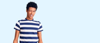 Genç Afro-Amerikalı sıradan kıyafetler giymiş, kameraya seksi bir ifadeyle bakıyor, neşeli ve mutlu bir yüzle.. 